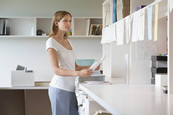 Ofis Çalışanı Elinde Kağıt Kağıtlarla Ofis Manzarasında Duruyor — Stok fotoğraf