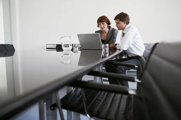 两名同事在会议桌旁使用笔记本电脑 — 图库照片