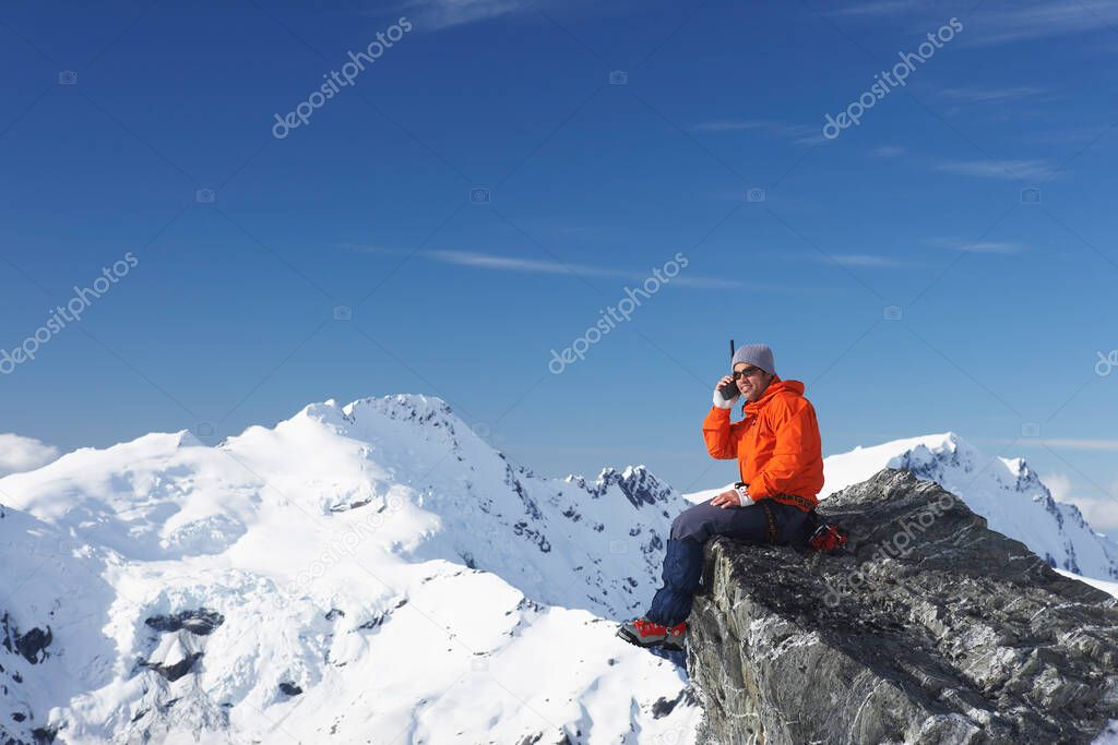 Mountain climber using walkie-talkie on mountain peak
