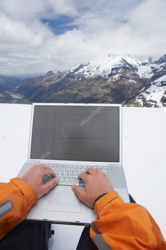 Man using laptop on snowy mountain peak close up of hands