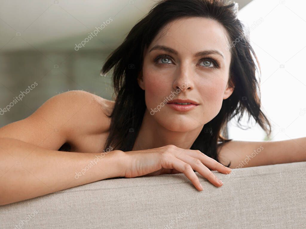 Young woman leaning on couch indoors close-up