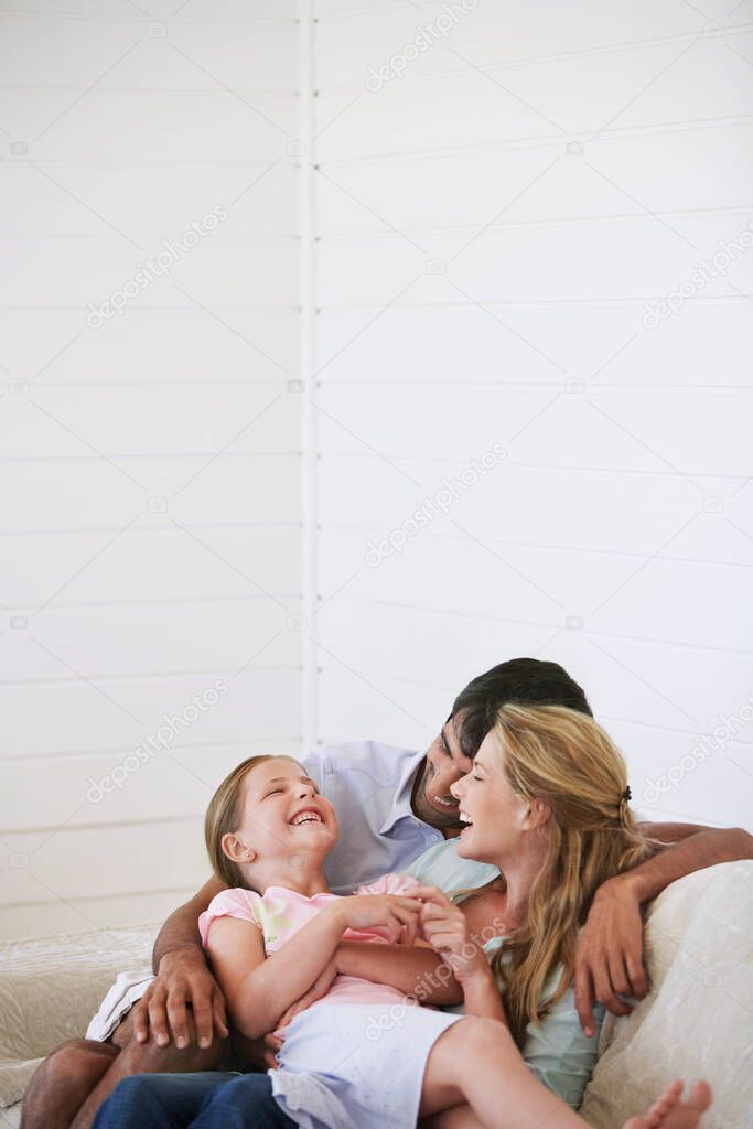 Parents with daughter cuddling on couch