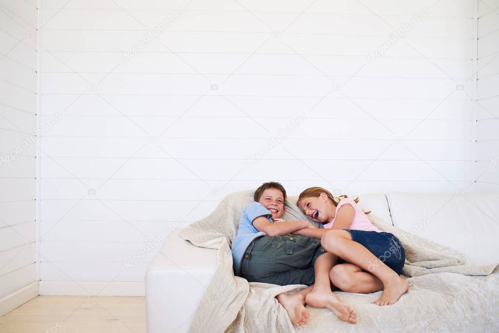 Young boy and girl laughing on couch in weatherboard room