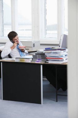 Ofisteki telefonda gülümseyen ve yemek yiyen bir iş adamı.