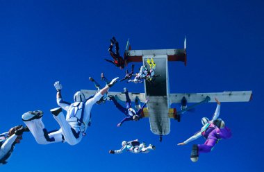 Group of skydivers jumping out of airplane low angle view clipart
