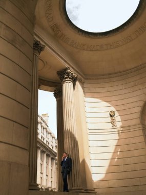 Neo-klasik biçim binasında cep telefonu kullanan bir işadamı