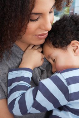 Çocuk (5-6) annesinin kollarında uyuyor.