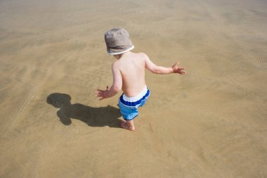 Oğlan (3-4) plaj arka görünümünde oynuyor