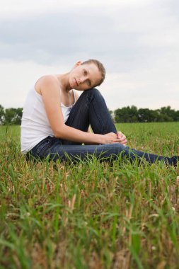 Serene genç bayan çayırda oturuyor