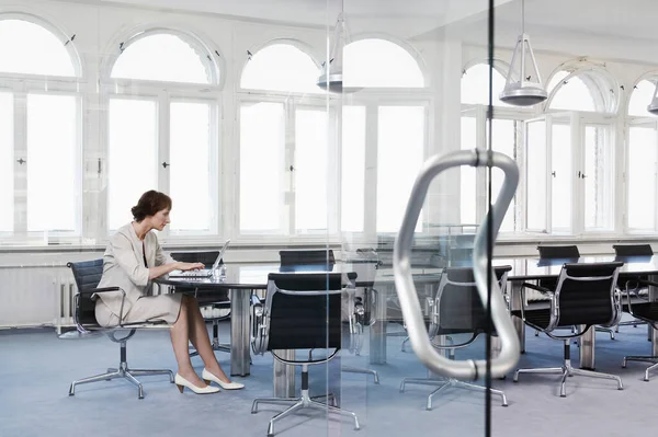 会議室のテーブルでノートパソコンを使うビジネス女性 — ストック写真