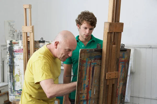 在艺术工作室里 学生们看着画家在画架上画画 — 图库照片