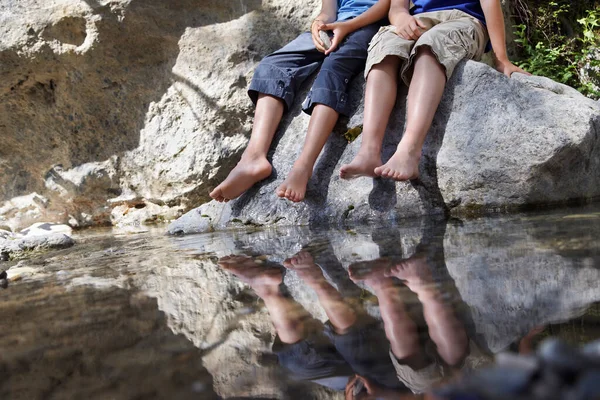 两个男孩 坐在岩石上 旁边是河流的低洼地 — 图库照片
