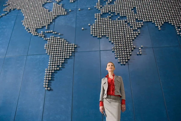 Mujer Negocios Sosteniendo Teléfono Móvil Frente Mapa Del Mundo Oficina —  Fotos de Stock