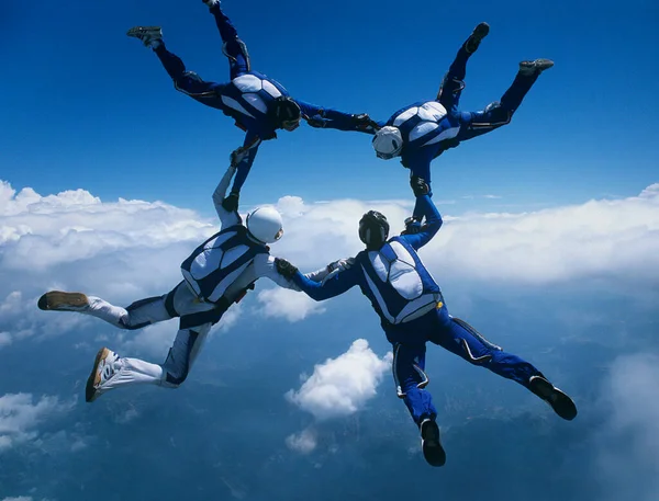 Vier Skydivers Houden Elkaars Hand Ring Tegen Wolken — Stockfoto