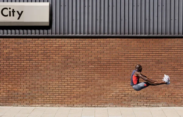 Man Springt Door Muur Met Stad Erop Geschreven — Stockfoto