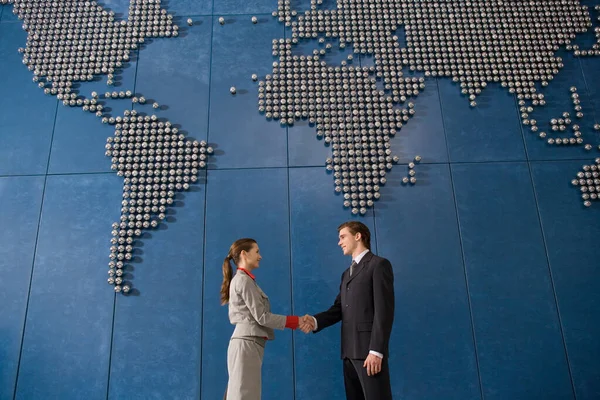 Compañeros Negocios Estrechando Las Manos Frente Mapa Del Mundo Pared — Foto de Stock