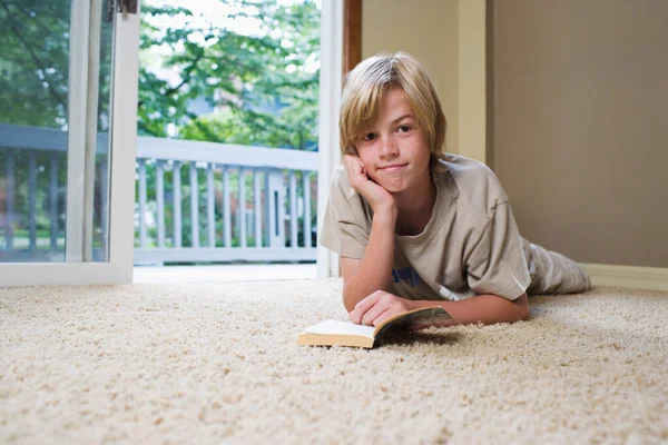 12岁 躺在地毯上看书的画像 — 图库照片