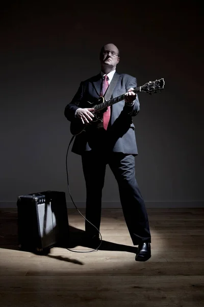 Man in full suit playing electric guitar