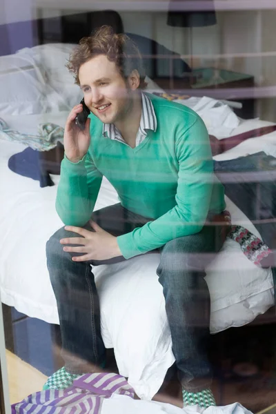 Hombre Usando Teléfono Móvil Sentado Cama Vista Través Ventana —  Fotos de Stock