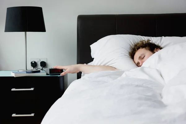 Mann Hält Hand Wecker Der Bett Liegt — Stockfoto