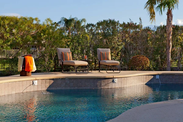 Chaise lounge chairs at poolside of manor house