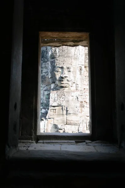 Stone Face Sculpture Seen Through Window of Ruins