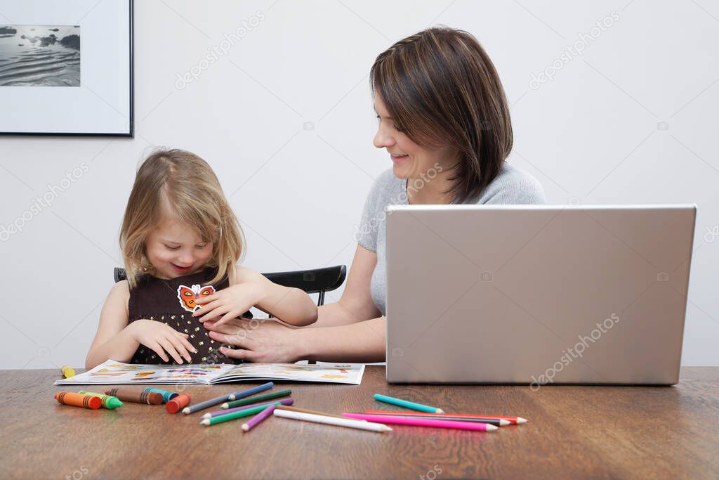 Mother playing with daughter (3-4) open laptop on table