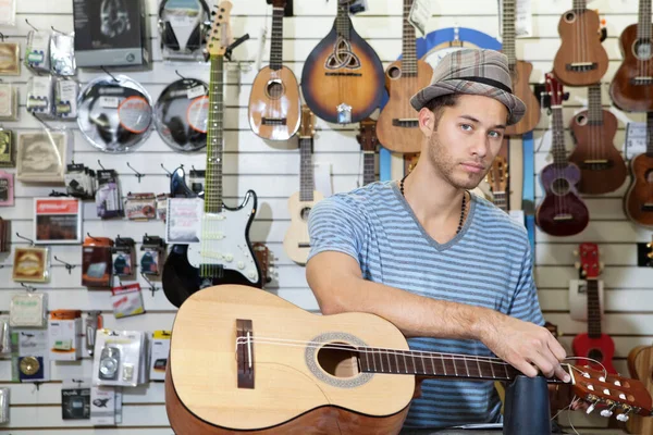 一个自信的男人在音乐商店里弹奏吉他的肖像 — 图库照片