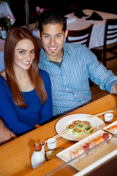 一对快乐的年轻夫妇在日本餐馆吃寿司的画像 — 图库照片
