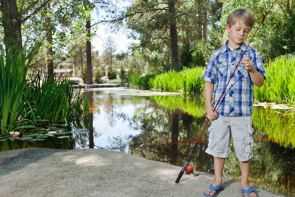 男孩站在湖边调整钓竿绳 — 图库照片