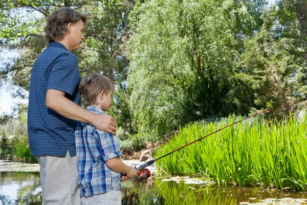 Side view of father and son fishing countryside