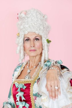 Kıdemli kraliçenin portresi pembe arka planda elini uzatıyor.