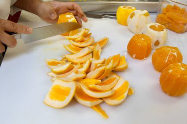 Portakalları bıçakla doğrayan ellerin yakın çekimi