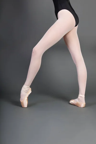 在灰色背景下穿着芭蕾拖鞋的年轻芭蕾舞者比例较低 — 图库照片