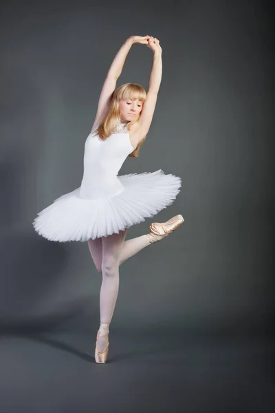 身着白色燕尾服的年轻女子在灰色背景下表演芭蕾舞 — 图库照片