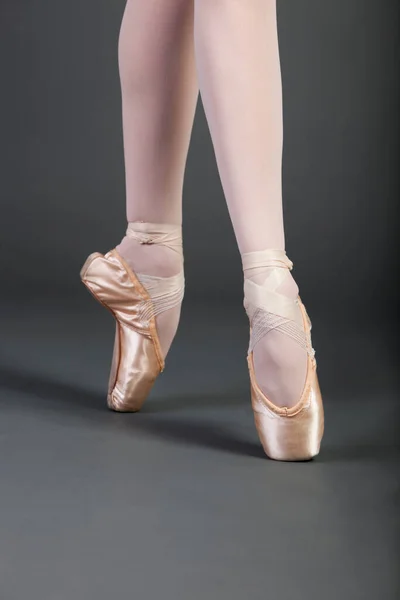 若いです女性バレエダンサーの低いセクションでは 足がグレーの背景の上にティッピングを越え — ストック写真