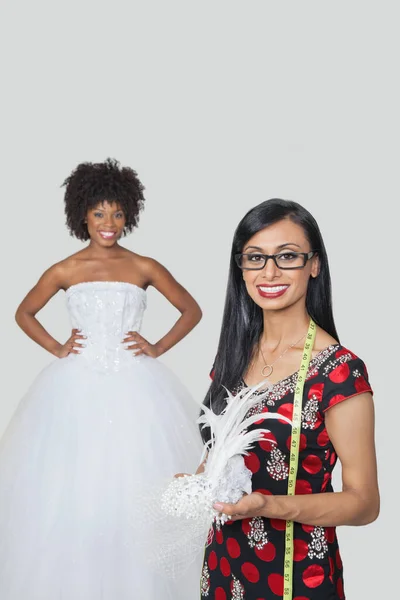 Indische Modedesignerin Mit Federkleid Und Afroamerikanischer Braut Vor Grauem Hintergrund — Stockfoto