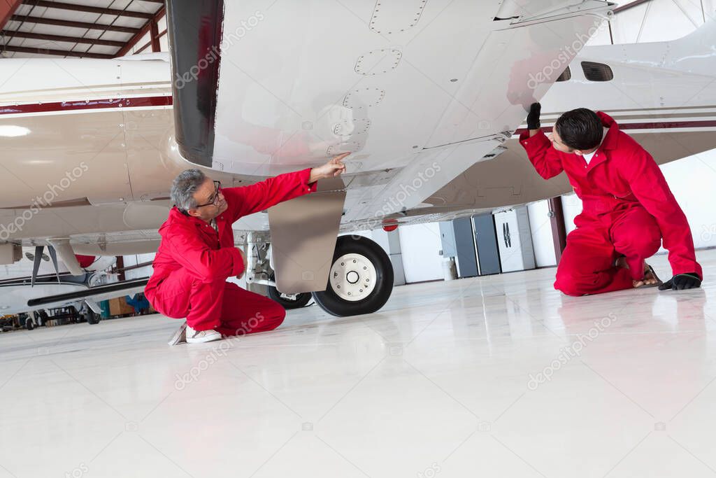 Aviation mechanics inspecting airplane wing