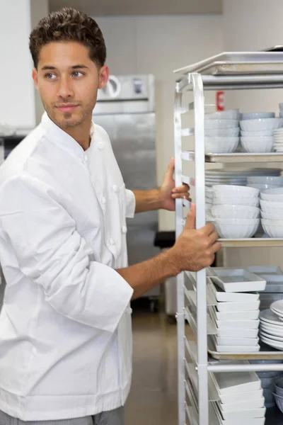 按器皿架排列的年轻男厨师 — 图库照片