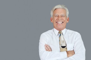 Gri arka planda kollarını kavuşturmuş neşeli kıdemli işadamının portresi