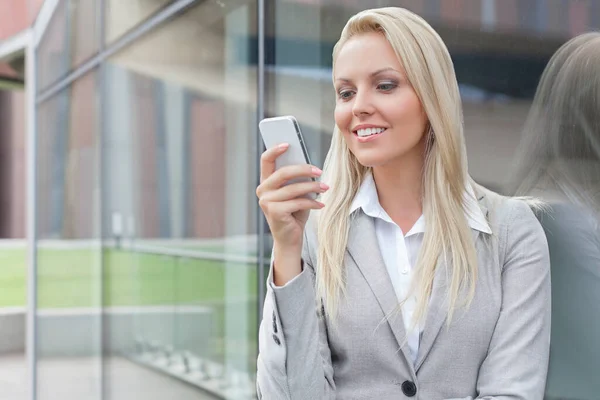 Mooie Jonge Zakenvrouw Sms Mobiele Telefoon Terwijl Leunen Glazen Wand — Stockfoto