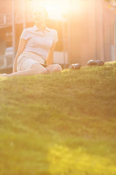オフィスの芝生に座っているリラックスした若いビジネスマンの女性 — ストック写真