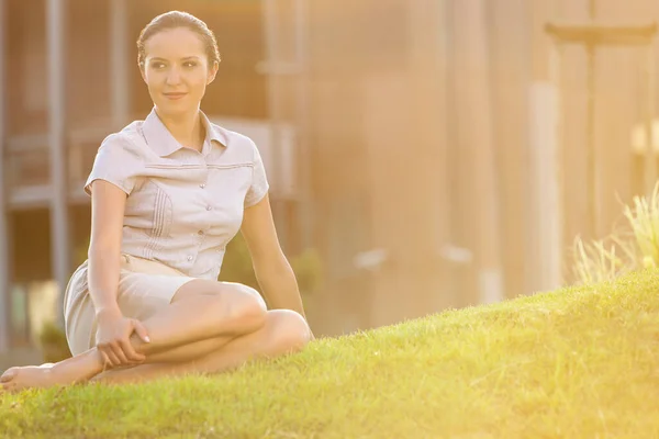 芝生の上に座っているリラックスした若いビジネスマンの女性 — ストック写真