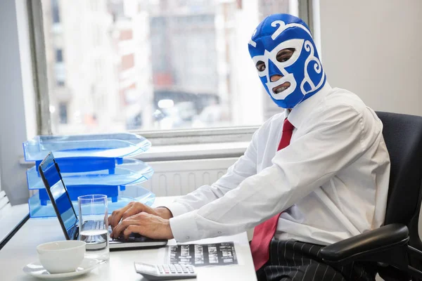 사무실 책상에서 레슬링 마스크를 노트북을 사용하는 사업가의 — 스톡 사진