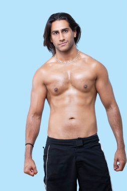 Portrait of shirtless young muscular man standing over blue background clipart