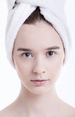 Kafasına havluyla sarılmış beyaz arka planda genç bir kadının portresi.