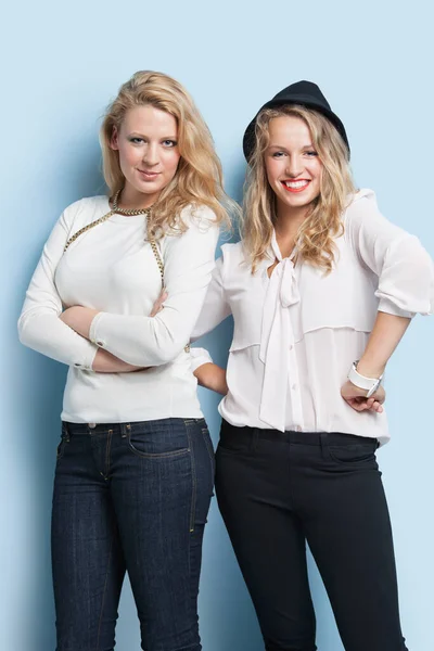 两个年轻女性朋友在浅蓝色背景下站在一起的画像 — 图库照片