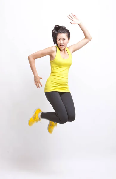 Портрет Молодой Азиатки Желтом Топе Леггинсах Прыгающих Белом Фоне — стоковое фото