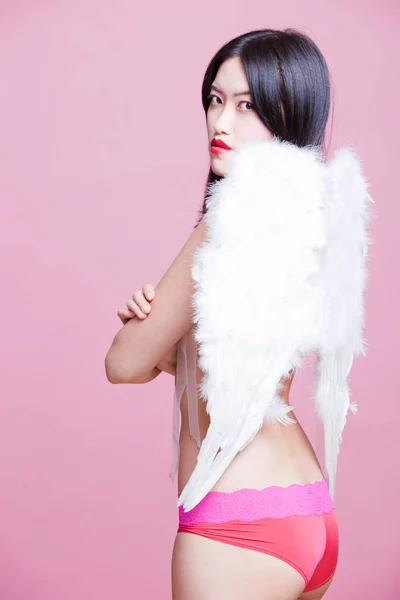 ピンクを背景に天使の翼を持つ若い女性の肖像画 — ストック写真