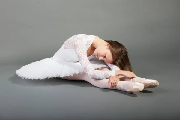 年轻的芭蕾舞蹈家穿着白色的燕尾服坐在灰色的背景上 — 图库照片